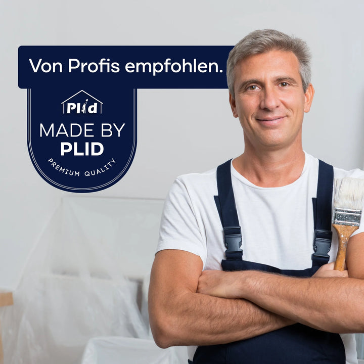 Ein lächelnder Mann in Latzhose mit einem Pinsel steht neben einem blauen Schild mit der Aufschrift "Von Profis empfohlen. MADE BY PLID PREMIUM QUALITY." Die Szene hebt Renovierungsarbeiten und das plid Abdeckvlies 220 g/m² schützende Oberflächen hervor.